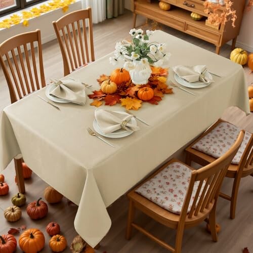 Dining table decorated with pumpkins and autumn leaves.