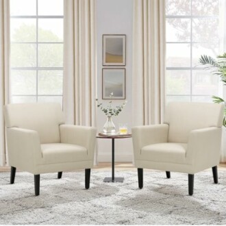 Two beige armchairs with a small table between them in a bright living room.