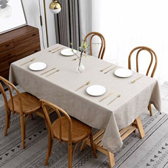 Dining table with beige tablecloth, wooden chairs, and minimalist place settings.
