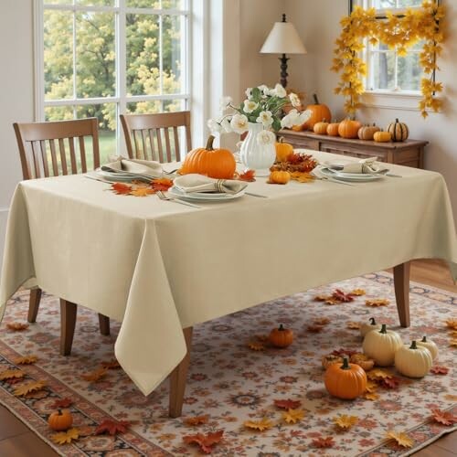 Dining table with fall decorations, pumpkins, and autumn leaves.