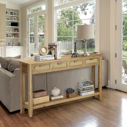 Wooden console table behind a sofa with books and decor in a bright living room.
