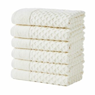 Stack of folded white towels with textured pattern.