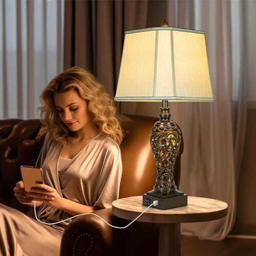Woman seated on a sofa using a phone beside an ornate lamp with USB charging.