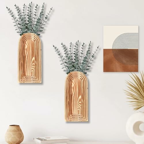 Wooden wall vases with eucalyptus branches and abstract art on white wall.