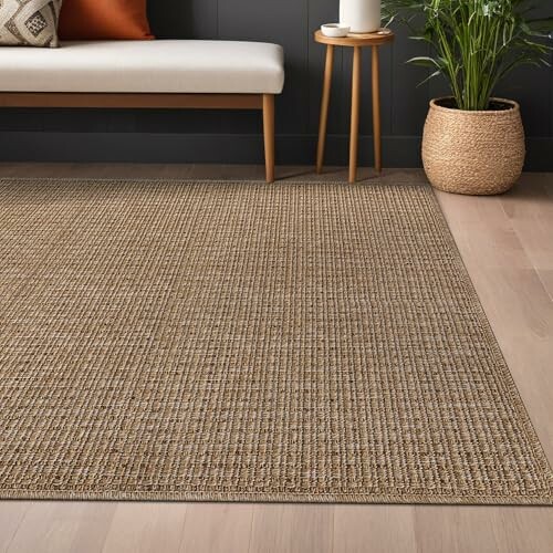 Woven jute rug in a modern living room with a bench, plant, and side table.